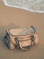 Skylaris Wanderer Duffel in Camel on a sandy beach.