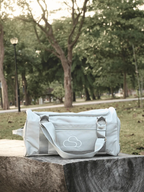 Skylaris Wanderer Duffel in Stone on a log in a park setting 